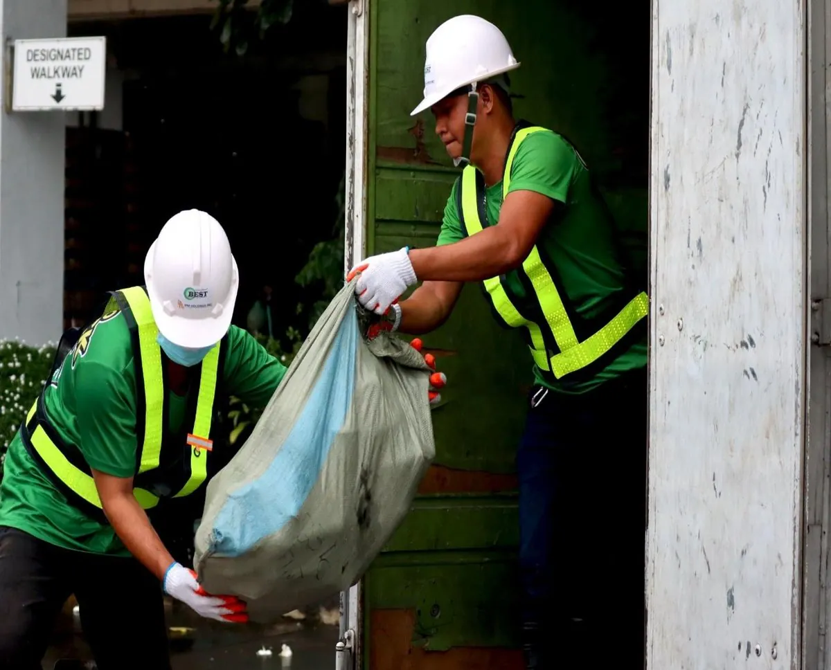 A BEST crew in hard hats receives a sorted bag at a doorway collection point
